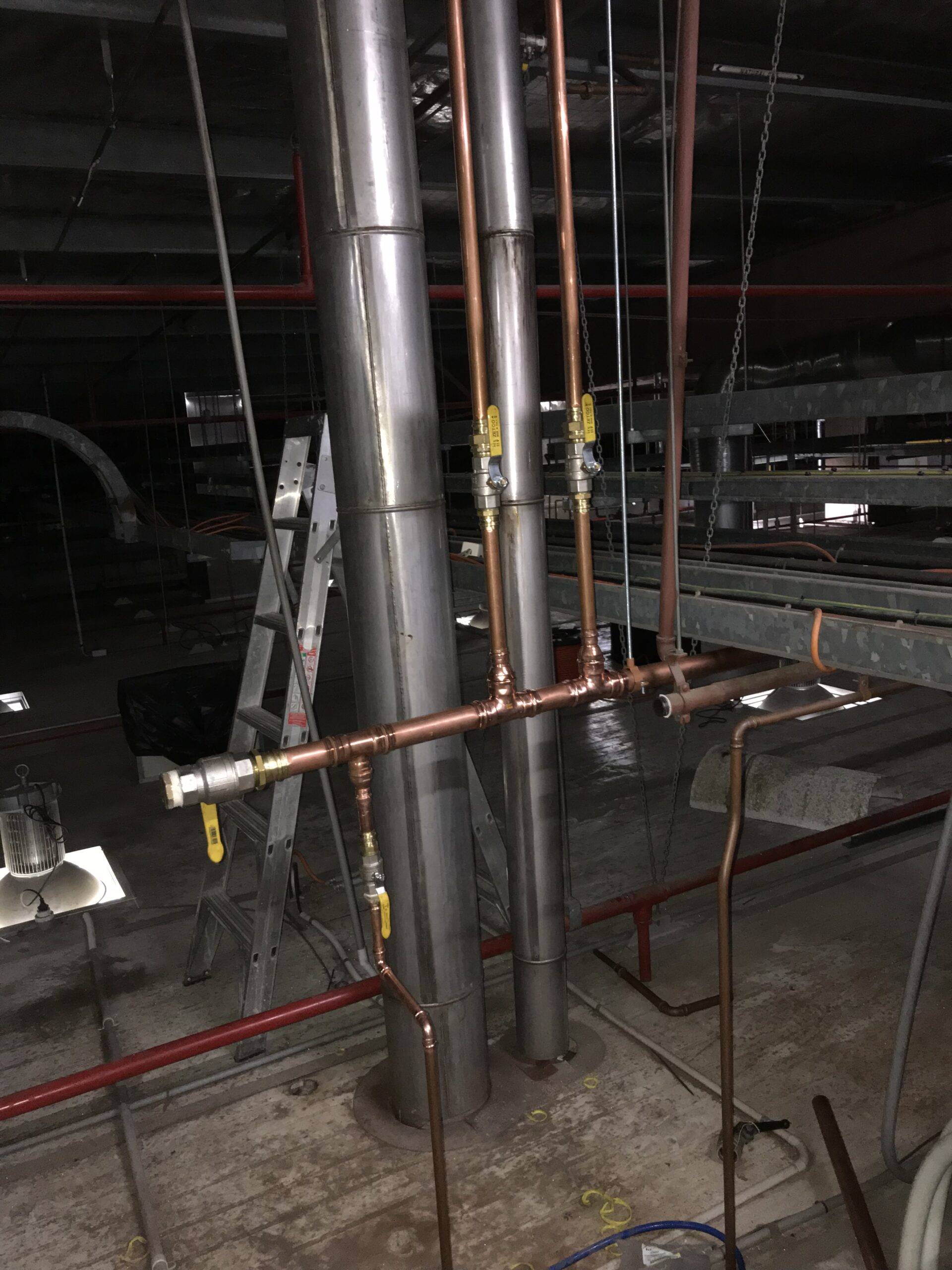 residential plumbing installation with copper pipes and metal ducts in construction site