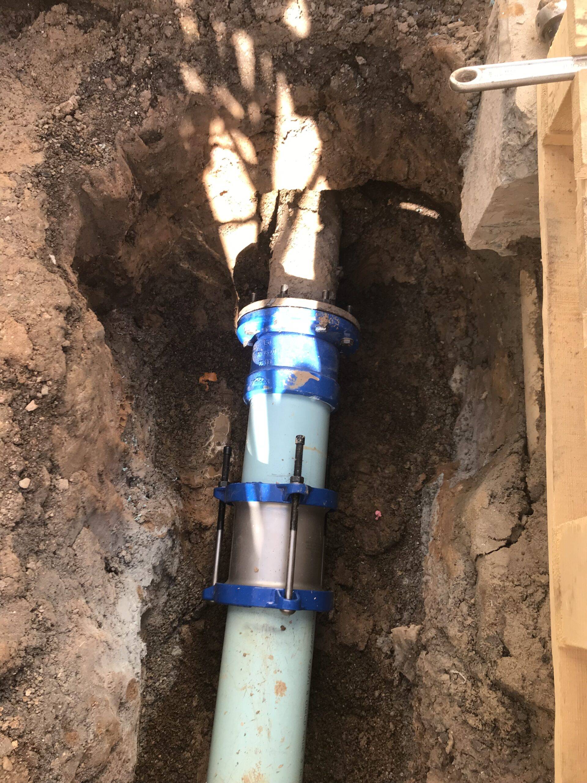 Underground pipe repair with blue coupling installed in excavated soil